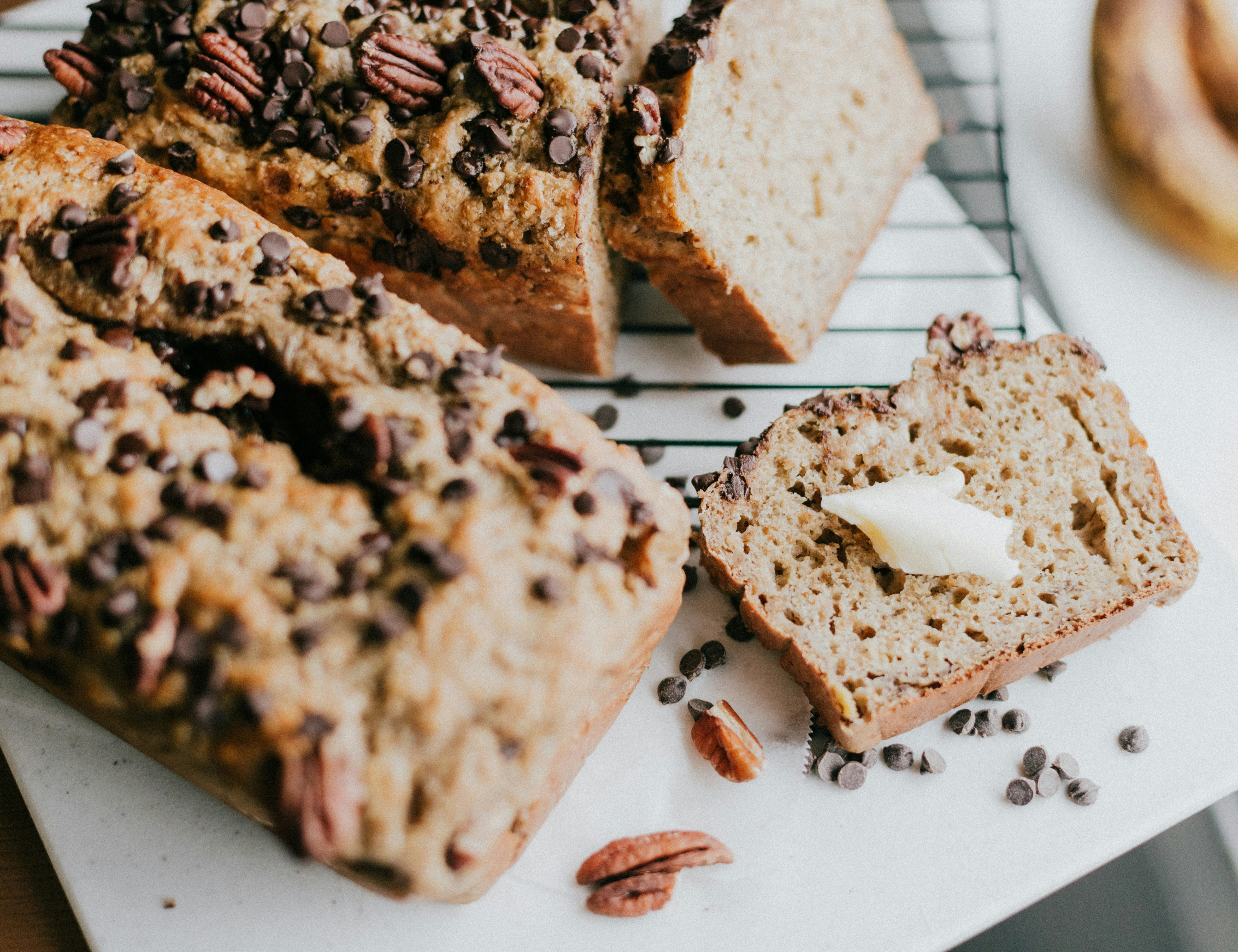 two loaves of banana bread with slices taken out of them on a square white plate